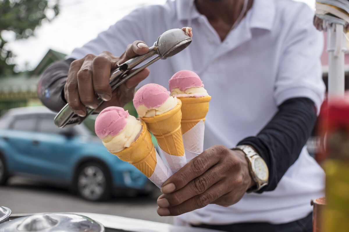A Sorbetero scoops strawberry and cheese sorbetes into in small wafer cones. Traditional ice cream in the Philippines.