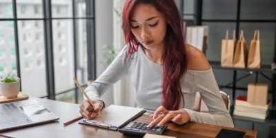 Woman managing small business accounts and recording sales revenue and expenses business income financial management entrepreneurship