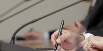 close up of conference meeting microphones and businessman writing