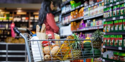 Various groceries in shopping cart in grocery section of supermarket