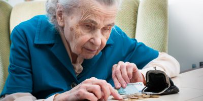 elderly caucasian woman counting money on table