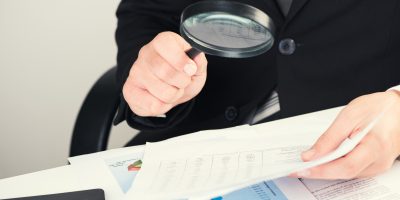 Businessman reading documents with magnifying glass concept for analyzing a finance