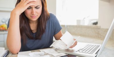 Brunette looking worried over bills in kitchen