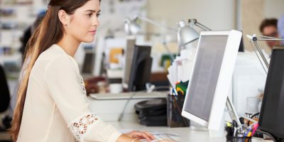Woman Working At Desk In Busy Creative Office