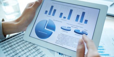 Close-up of a financial analyzer holding a digital tablet with statistical data