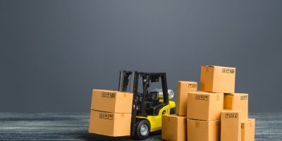 Yellow Forklift truck and cardboard boxes. Production, transport, cargo storage. Freight shipping. retail. Transportation logistics infrastructure, import and export goods and products delivery