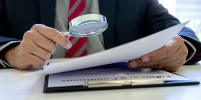 Lawyer or judge use magnifier glass look to the paper for inspection examination to the law case