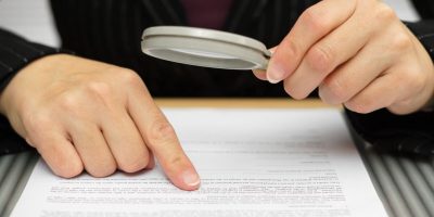 Businesswoman looking through a magnifying glass to contract