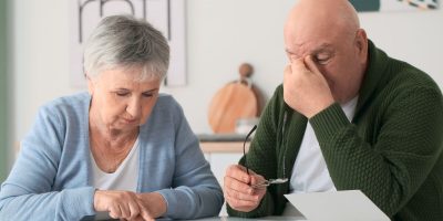 Stressed senior couple counting money at home