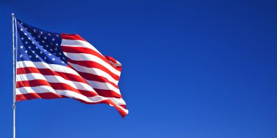 American flag waving in blue sky
