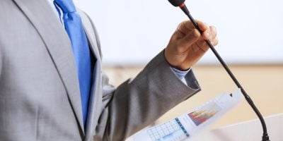 Businessman standing on stage and reporting for audience