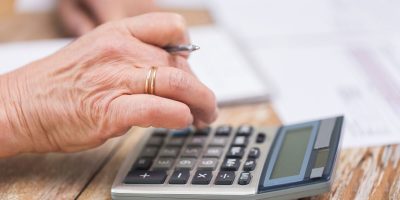 business, savings, annuity insurance, age and people concept - senior woman with calculator and papers counting at home